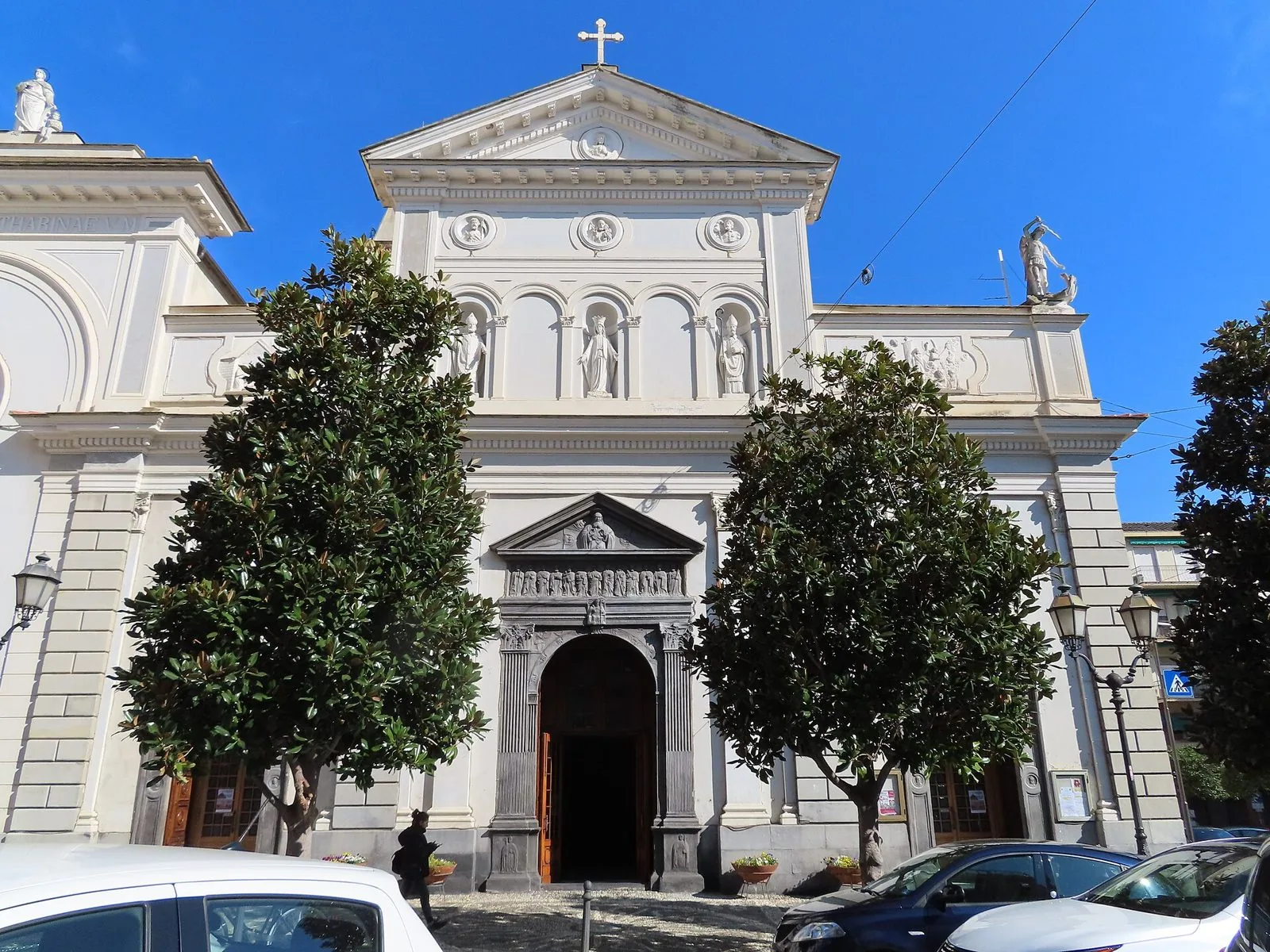 La facciata della collegiata di Sant'Ambrogio ad Alassio con il portale in ardesia tra due grandi alberi