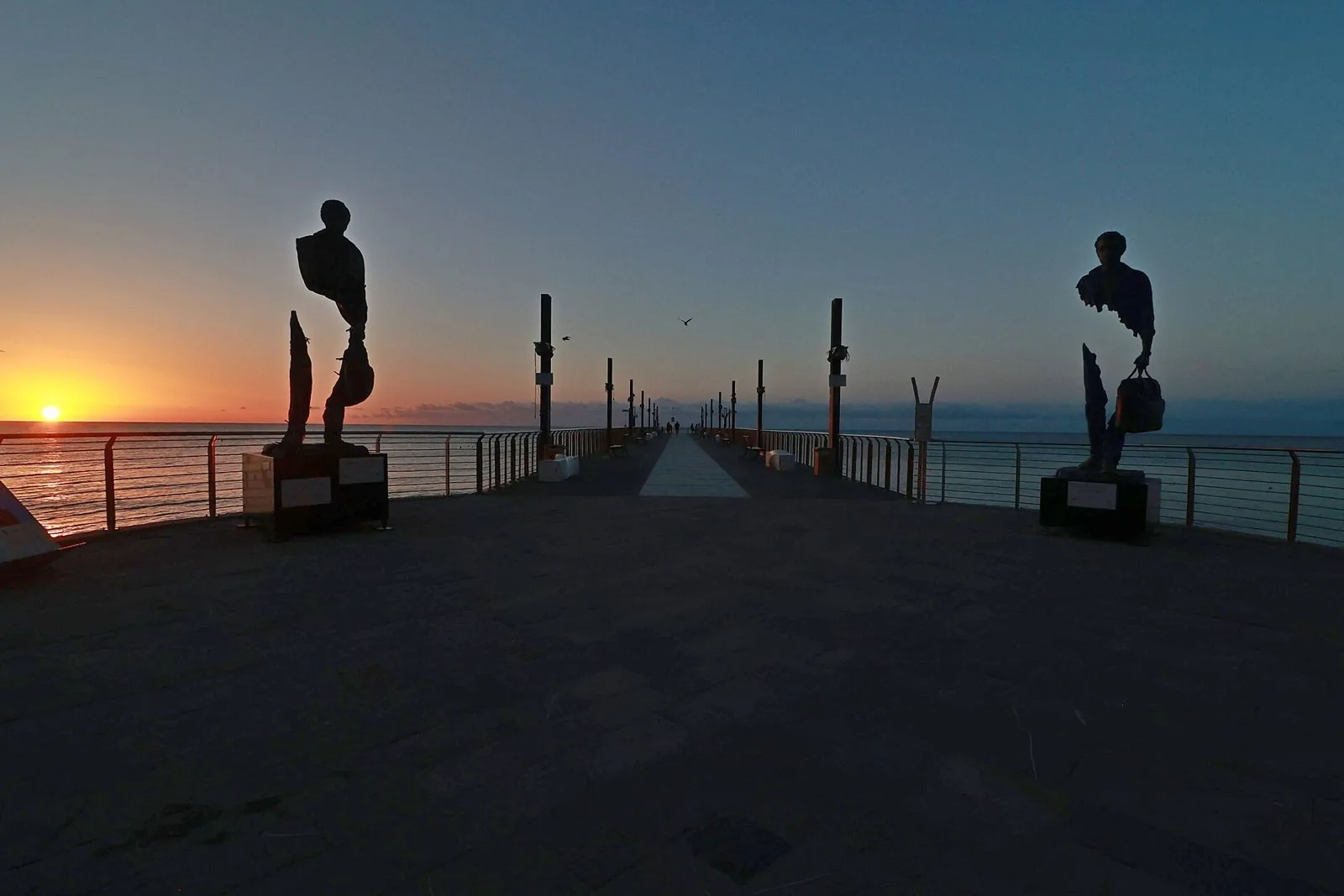 Il pontile Mario Bestoso di Alassio al tramonto, con le sculture in controluce sul mare